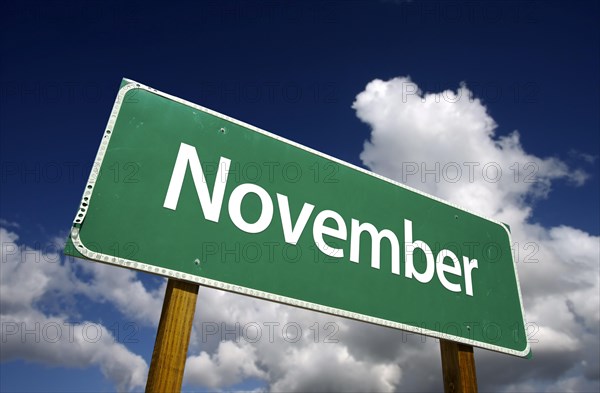 November green road sign with dramatic blue sky and clouds