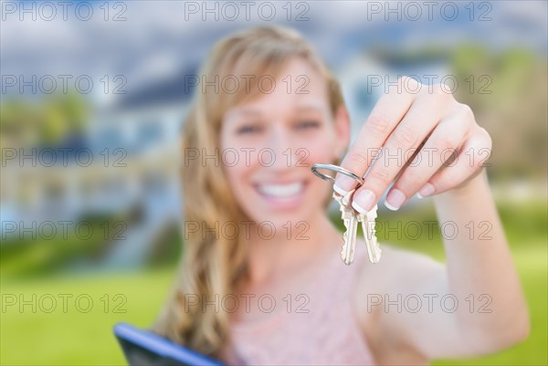 Excited woman holding house keys in front of nice new home