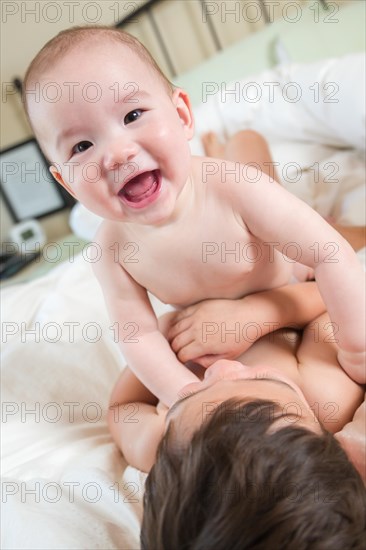 Young mixed-race chinese and caucasian baby brothers having fun on their blanket