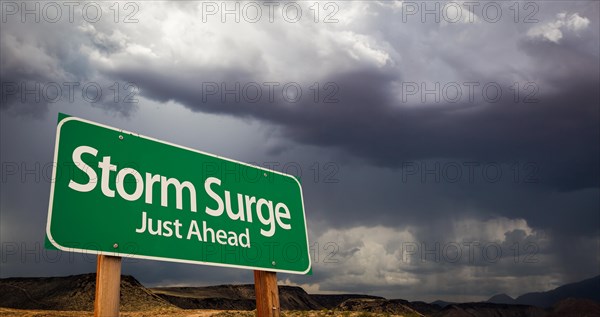 Storm surge just ahead green road sign with dramatic clouds and rain