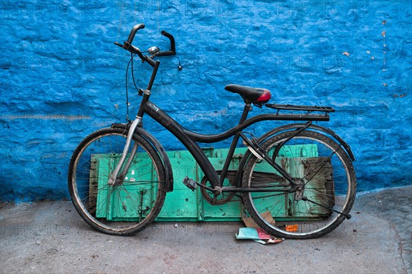 Old bicycle at the wall of blue house in streets of of Jodhpur