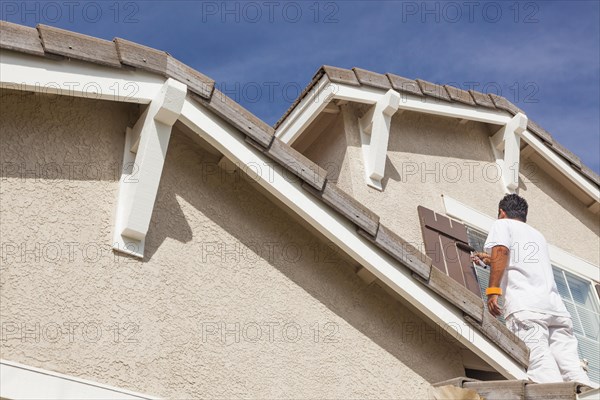 Busy house painter painting the trim and shutters of A home