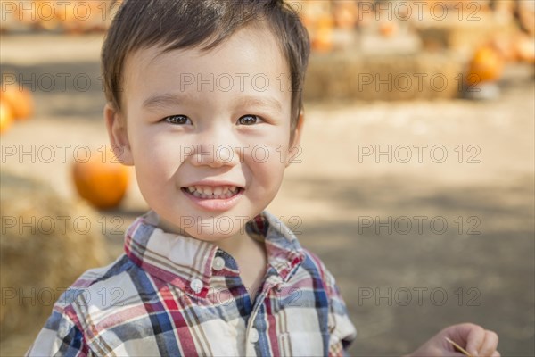 Cute mixed-race young boy having fun at the pumpkin patch