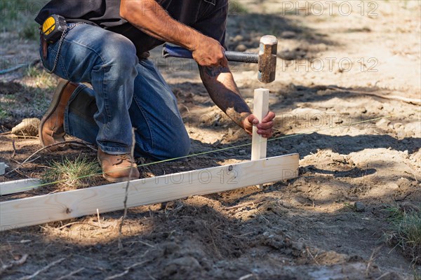 Worker installing stakes and lumber guides at construction site
