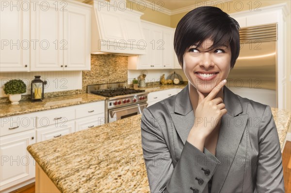 Pretty mixed-race woman looking back over shoulder inside custom kitchen interior