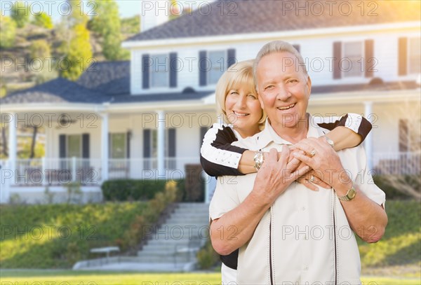 Happy senior couple in the front yard of their house