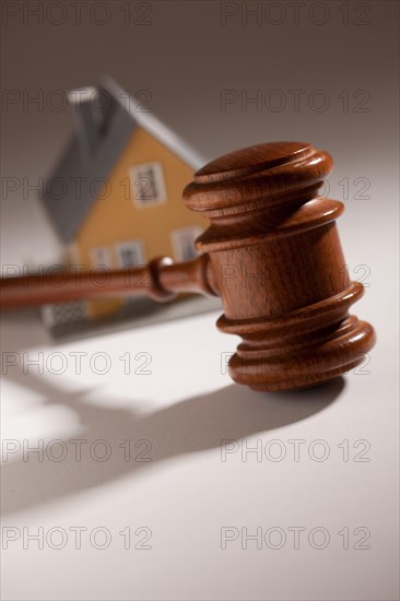 Gavel and model home on gradated background with selective focus