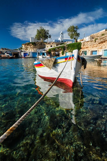 Fishing boats moored in crystal clear turquoise sea water in harbour in Greek fishing village of Mandrakia