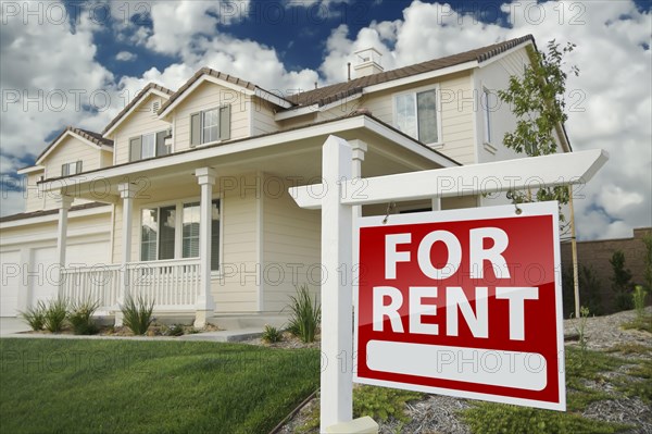 Left facing red for rent real estate sign in front of beautiful house