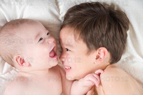 Young mixed-race chinese and caucasian baby brothers having fun on their blanket