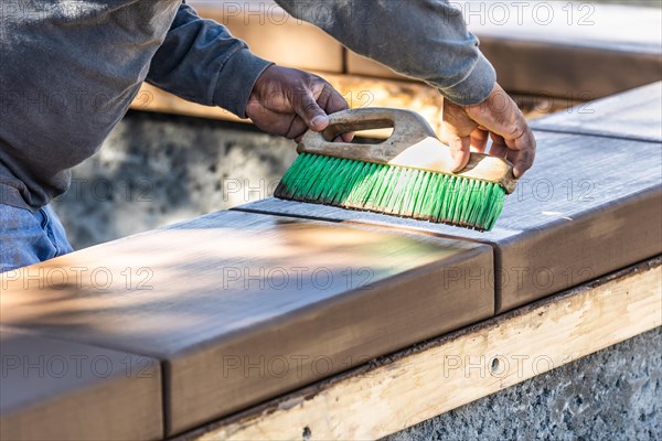 Construction worker using brush on wet cement forming coping around new pool