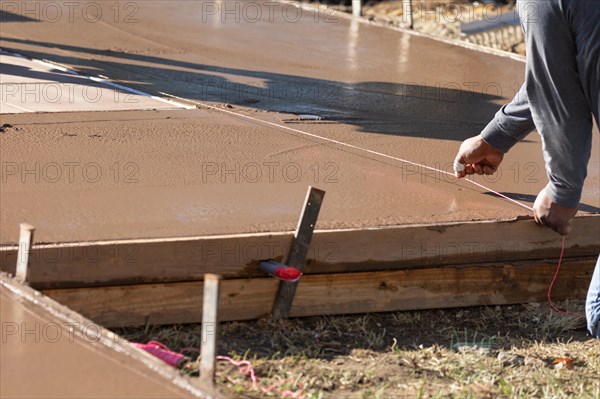 Construction worker snapping line into wet deck cement