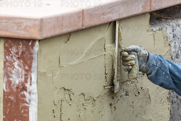 Tile worker applying cement with trowel at pool construction site