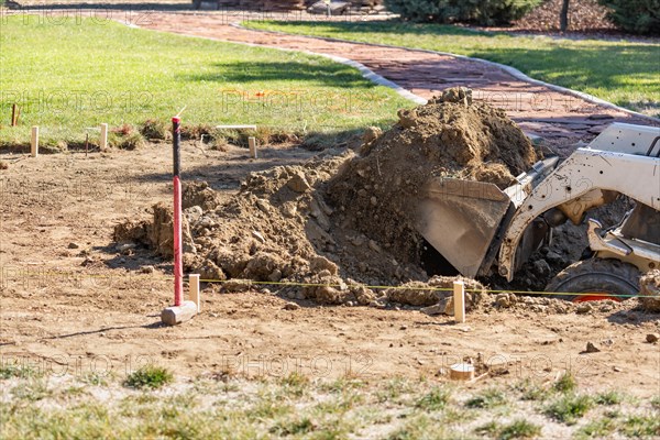 Small bulldozer digging in yard for pool installation