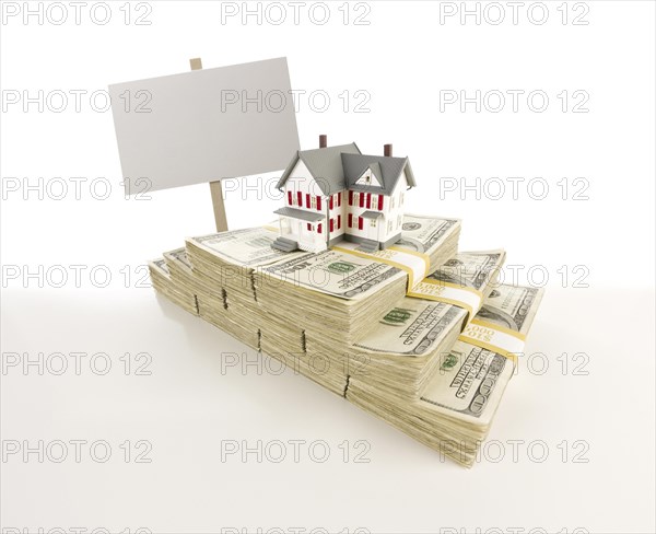 Stacks of one hundred dollar bills with small house and blank sign on slight gradation