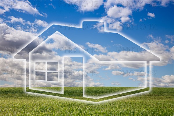 Dreamy house icon over empty grass field and deep blue sky with clouds