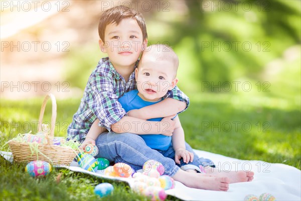 mixed-race chinese and caucasian boys outside in park playing with easter eggs