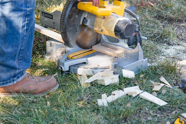 Worker using electric miter saw at constrcution site