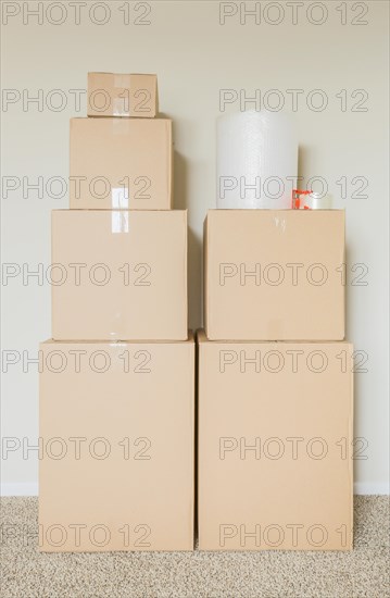Variety of packed moving boxes with materials in empty room against wall
