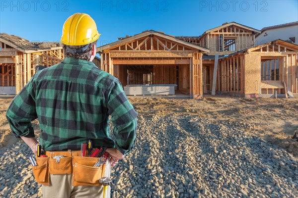 Contractor in front new house wood framing at construction site