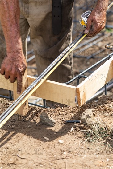 Worker measuring steel rebar at construction site