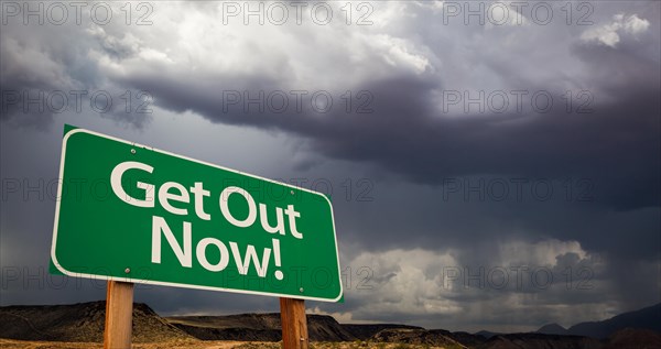 Get out green road sign with dramatic clouds and rain