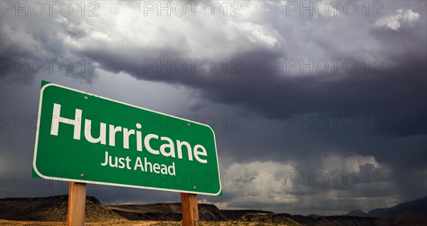 Hurricane just ahead green road sign with dramatic clouds and rain