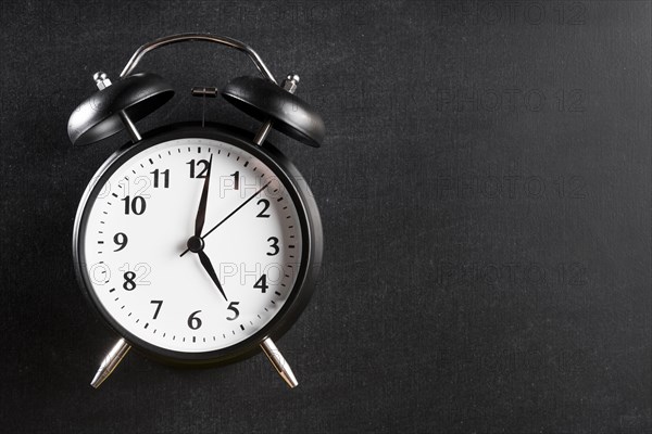 Alarm clock showing 5 o clock against black background