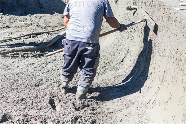 Pool construction worker working with A bullfloat on wet concrete