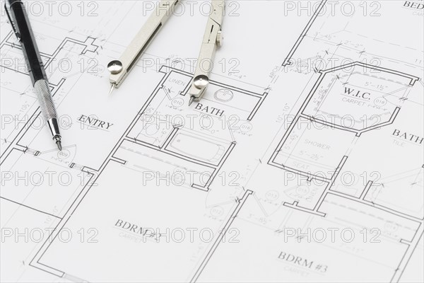 Engineer pencil and compass resting on custom house plans