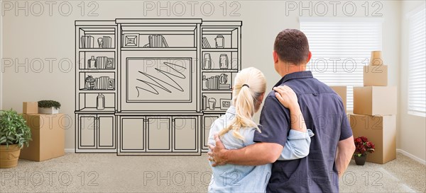 Couple inside empty room with moving boxes facing entertainment unit drawing on wall