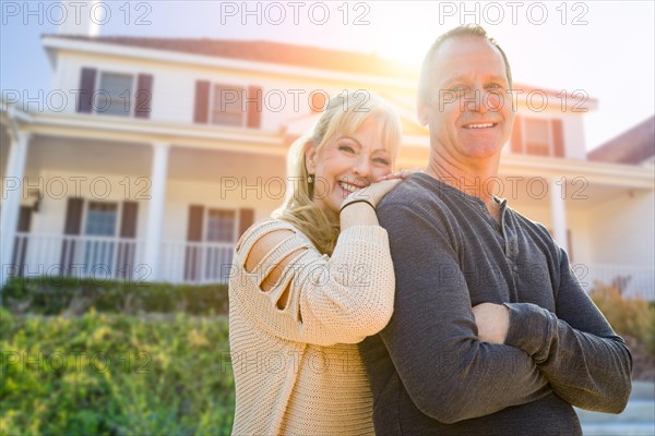 Attractive middle-aged couple in front of their house