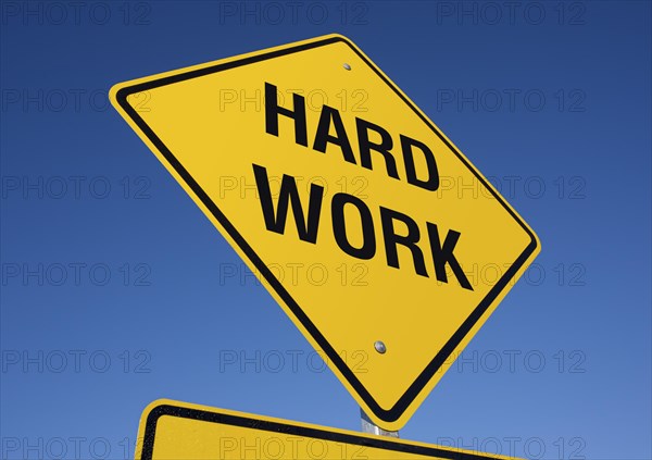 Yellow hard work road sign against a deep blue sky with clipping path