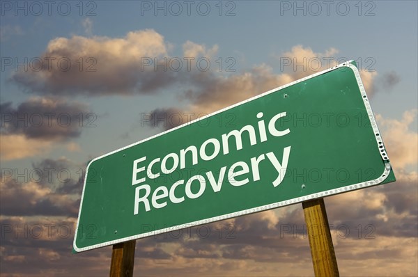 Economic recovery green road sign with dramatic clouds and sky