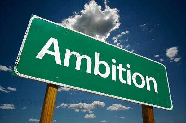 Ambition green road sign over dramatic sky and clouds