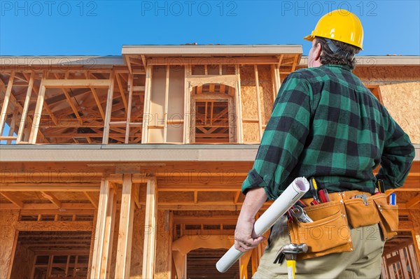 Contractor in front new house wood framing at construction site