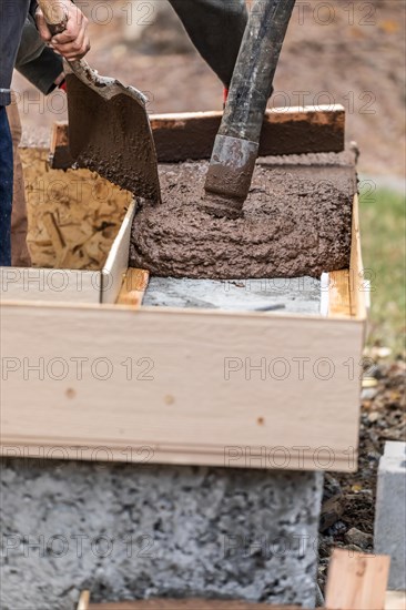 Construction workers pouring and leveling wet cement into wood framing