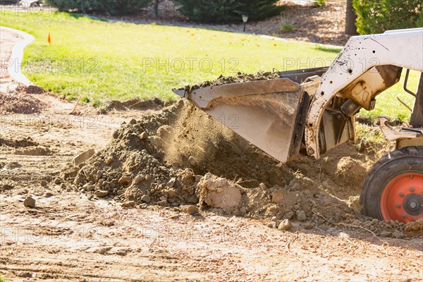 Small bulldozer digging in yard for pool installation