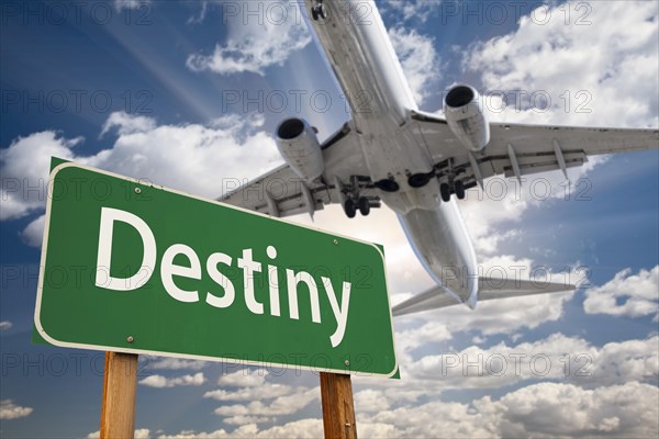 Destiny green road sign and airplane above with dramatic blue sky and clouds