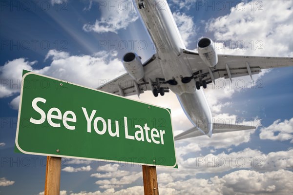 See you later green road sign and airplane above with dramatic blue sky and clouds