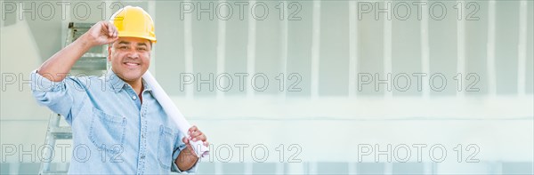 Hispanic male contractor wearing hard hat against drywall banner background with ladder