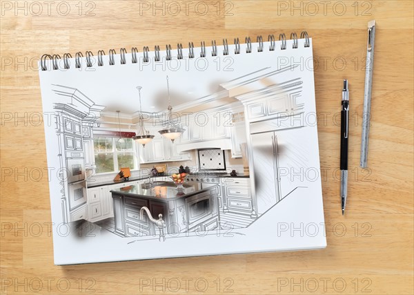 Sketch pad on desk with drawing of custom kitchen and brush stroke showing finished construction next to engineering pencil and ruler scale