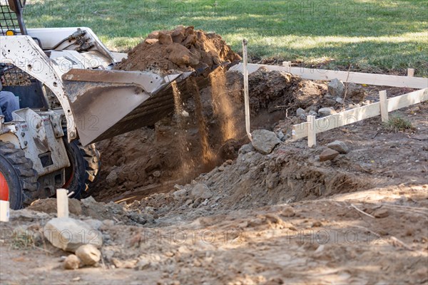 Small bulldozer digging in yard for pool installation