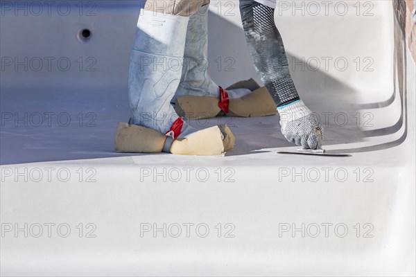 Worker wearing sponges on shoes smoothing wet pool plaster with trowel