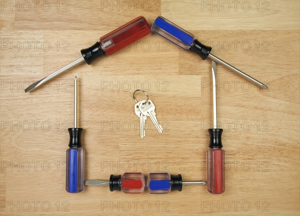 House shaped by screwdrivers and keys on a wood background