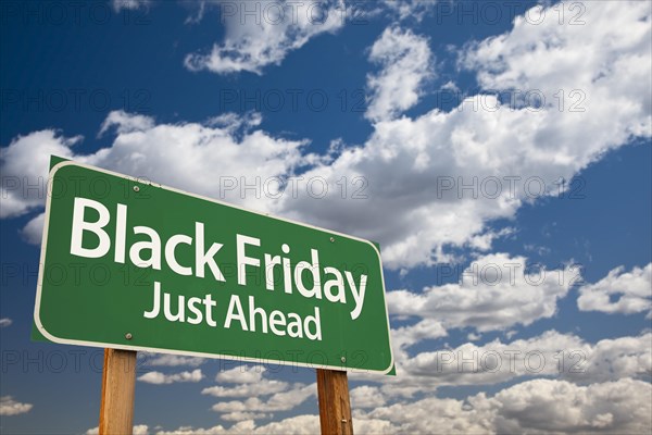 Black friday just ahead green road sign with dramatic clouds and sky