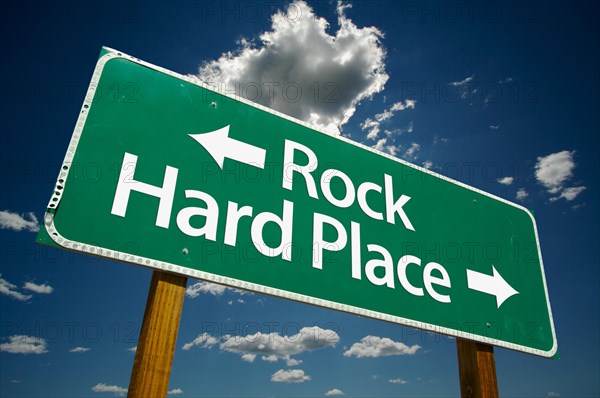 Rock and hard place green road sign with dramatic clouds and sky