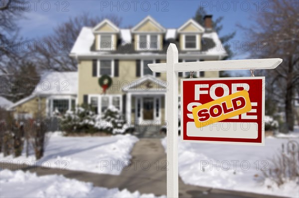 Sold home for sale real estate sign in front of beautiful new house in the snow