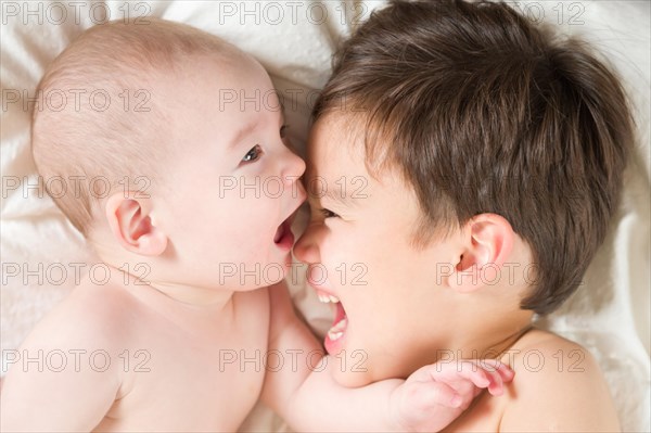 Young mixed-race chinese and caucasian baby brothers having fun on their blanket