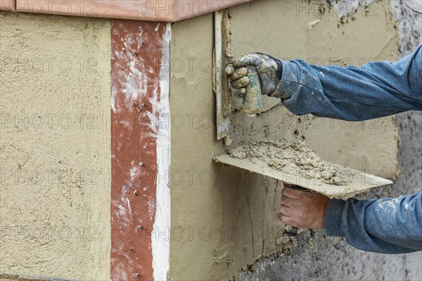 Tile worker applying cement with trowel at pool construction site